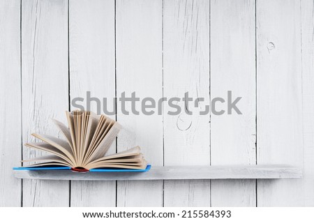 The open book on a wooden shelf. A wooden, white background.