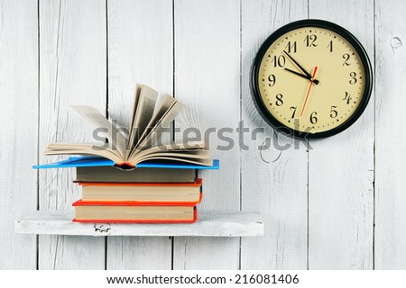 The open book on a wooden shelf and watches. On a white, wooden background.