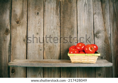 Tomatoes in a basket on a wooden shelf. On a wooden background.