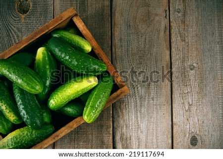 Cucumbers in a box on a wooden background.