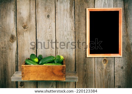 Cucumbers in an old box on a wooden shelf. Framework on a wooden background.