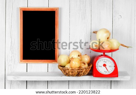 Onions on scales and in a basket on a wooden shelf. A framework on a wooden background.