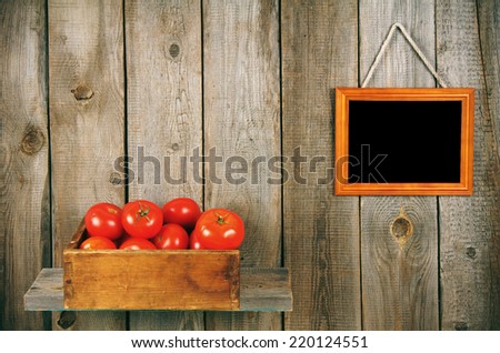 Tomatoes in an old box on a wooden shelf. Framework on a wooden background.