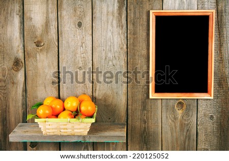 Tangerines in a basket on a wooden shelf. A framework on a wooden background.