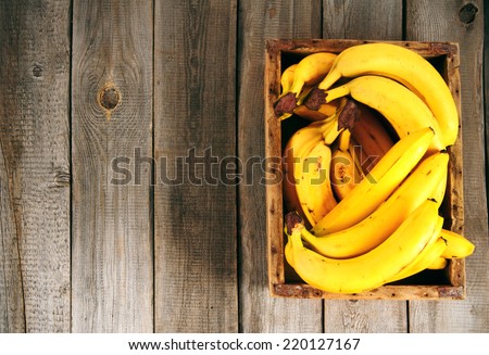 Bananas in a box on a wooden background.