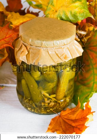 Autumn concept. Preserved food in glass jar on a wooden board. Marinated gherkins