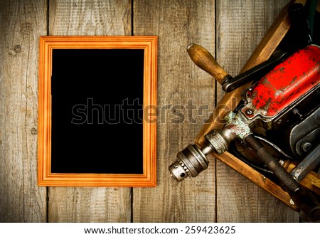 Old working tools. Frame with old tools (drill, mallet, saw and others) in a box on a wooden background.