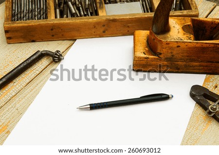 Old working tools. Paper with pencil and the vintage working tools on wooden background.