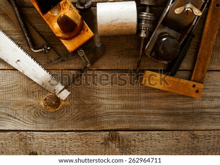 The old working tool. Many old working tools (plane, drill, mallet and others) on a wooden background.