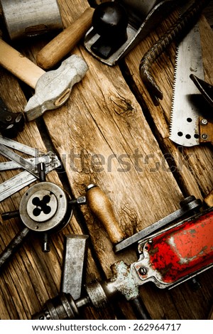 Old working tools. Vintage working tools (drill, saw, ruler and others) on wooden background.