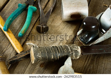 The old working tool. Many old working tools (mallet, plane, hammer and others) on a wooden background.