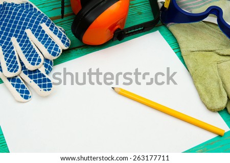Working tools. A paper with pencil and the working tool (gloves, glasses and others) on wooden, green background.