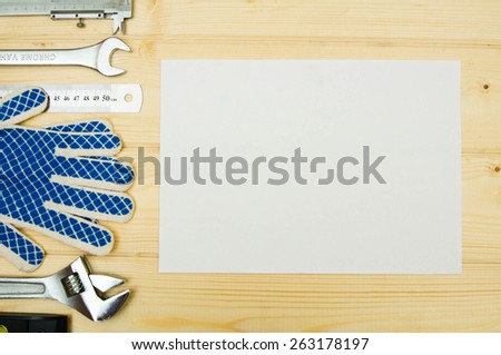Workng tools. Paper for notes and set of working tools (gloves, clamp , wrench and others) on wooden background.