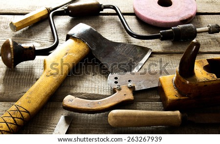 The old working tool. Many old working tools ( axe, saw and others) on a wooden background.