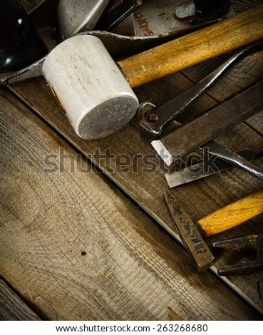 The old working tool. Many old working tools (mallet, plane, hammer and others) on a wooden background.