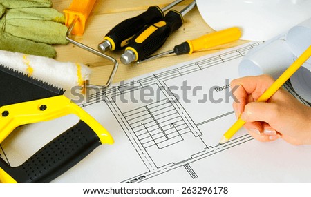 Planning of repair of the house. Repair work. Drawings for building, women hand, saw and others tools on wooden background.