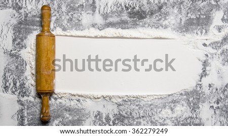 Preparation of the dough. The rolling pin with flour on a stone background. Free space for text. Top view