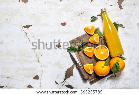 Fresh orange juice with oranges, leaves and a knife. On rustic background. Free space for text . Top view