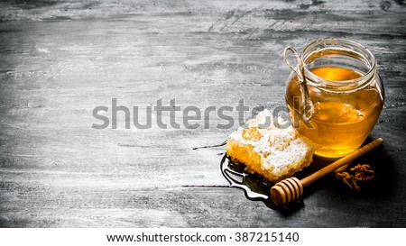 Honey background. Natural honey comb and a glass jar. On black rustic table.