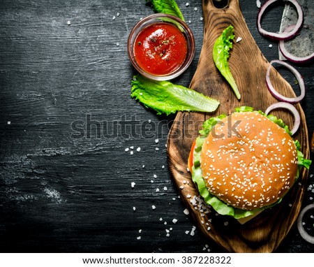 The Burger and the fresh ingredients on the old Board. On a black chalkboard.  Top view.