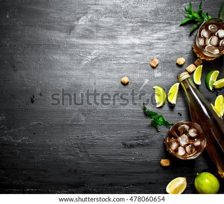 Rum with ice , mint and fresh lime. On a black wooden background.