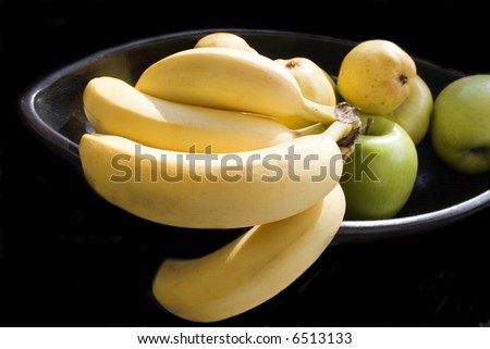 pears, apples and bunch of bananas in black Japanese vase isolated with black background 1