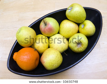 Black Japanese vase with apples and tangerine served at wooden table