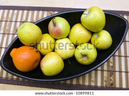 Black Japanese vase with apples and tangerine served at wooden table