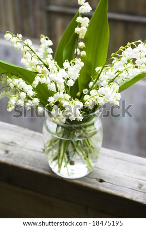 bouquet of lily of the valley in glass vase at the wood handrail