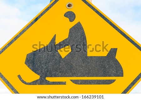 Close-up of a yellow and black snowmobile road warning sign against a blue sky, Alaska, US