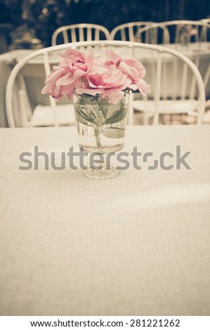 Pink rose in the glass vase on the table in the garden restaurant, vintage style