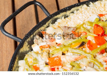 Paella rice with prawns cooked in a barbecue fire