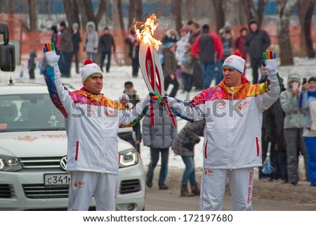 Novosibirsk, Russia - December 7, 2013 - two torchbearers set fire Olympic flame in relay of Olympic flame.