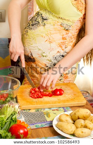 pregnant woman\'s hands and belly cutting  on kitchen with healthy food. The concept of food and a healthy lifestyle
