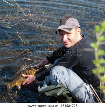 Happy lucky fisherman holding a big carp on the river. Early morning on fishing