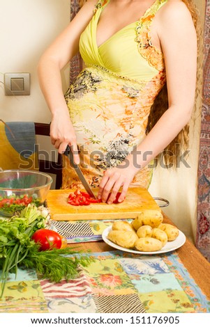 pregnant woman s hands and belly cutting on kitchen with healthy food The concept of food and a healthy lifestyle