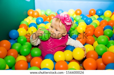 Happy child girl in colored ball on playground  The concept of childhood and holiday