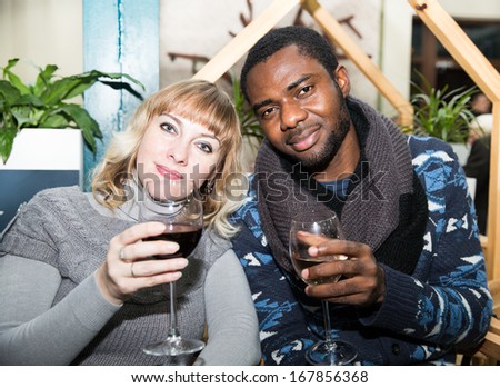 Portrait of happy couple  black man and white woman with glass of wine at party