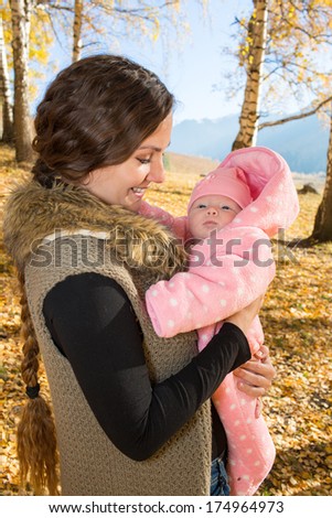 Happy mom and child girl hugging and laughing on nature fall. The concept of cheerful childhood and family. Beautiful Mother and her baby