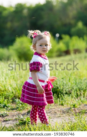 Adorable little child girl on grass on meadow. Summer green nature background