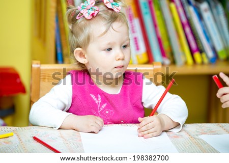 Child girl drawing with colorful pencils in preschool at the table. Little girl and boy drawing in kindergarten