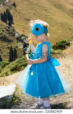 Adorable little child girl with bubble blower on grass on meadow. Summer green nature .  Use it for baby, parenting or love concept