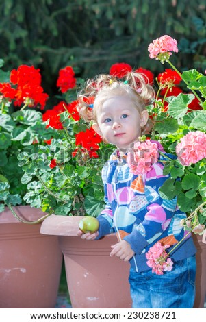 Adorable little child girl in park near flower Bed in summer day. Use it for baby, parenting or love concept