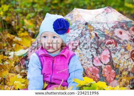 Fall. Cute child girl playing with fallen leaves in autumn park