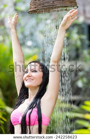 Sexy woman with long hair in bikini under the shower on tropical beach . Sea and water background