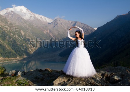 beautiful sexy bride in a long white dress against the backdrop of the lake and mountains