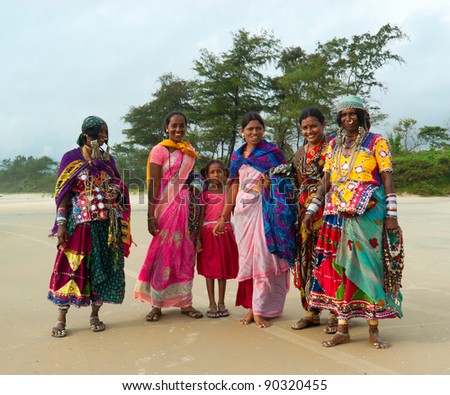 GOA, INDIA - SEPTEMBER 18: Unidentified Indian women and children in traditional dress pose for tourist photos on Goa beach, September 18, 2011 in Goa, India. This activity will provide a income stream for poor women on this Indian state