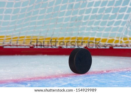 Hockey puck stand on side in front of goal net. Close view