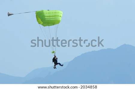 A tandem parachute jump nears landing with the Boulder, CO Flatirons in the background.
