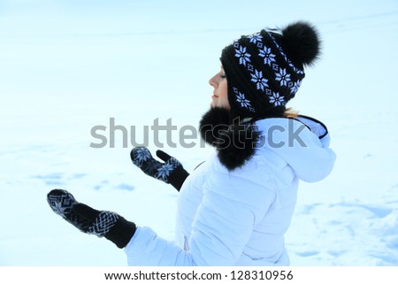 Beautiful woman in warm clothing with snow, catching snowflakes